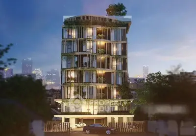 Luxurious modern building with lush greenery and city skyline view at dusk.