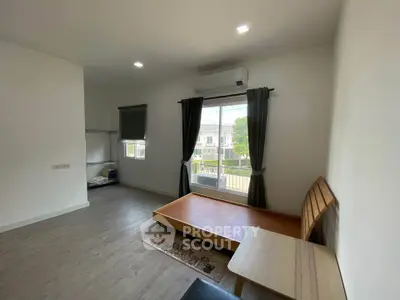 Spacious minimalist bedroom with large window and modern furnishings