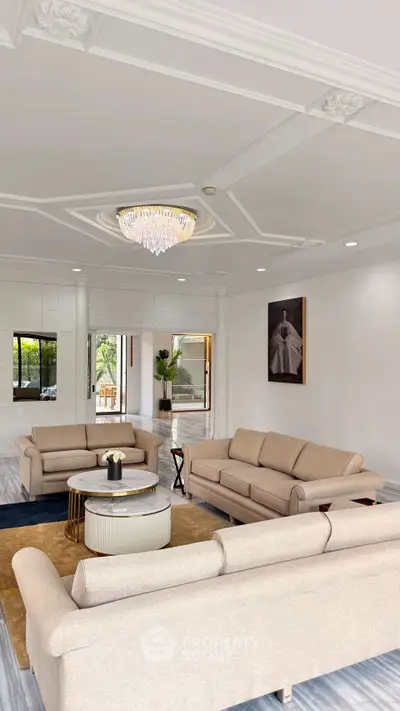 Elegant living room with luxurious chandelier and modern beige sofas, perfect for sophisticated gatherings.