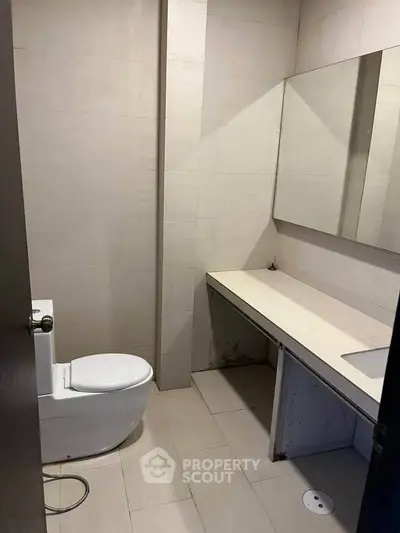 Modern bathroom with sleek design and spacious layout, featuring a large mirror and contemporary fixtures.