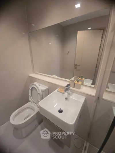 Modern bathroom with sleek fixtures and large mirror in a contemporary apartment.