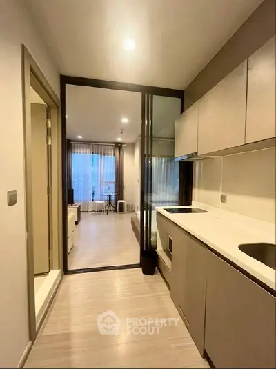 Modern kitchen with sleek cabinetry and open layout leading to a bright living area.