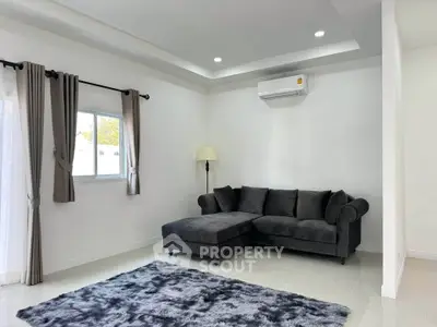 Modern living room with stylish gray sofa, plush rug, and sleek air conditioning unit.