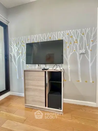Modern living room with stylish TV stand and wall art, featuring wooden flooring and natural light.