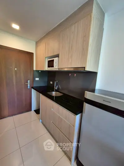 Modern compact kitchen with sleek cabinetry and built-in appliances.