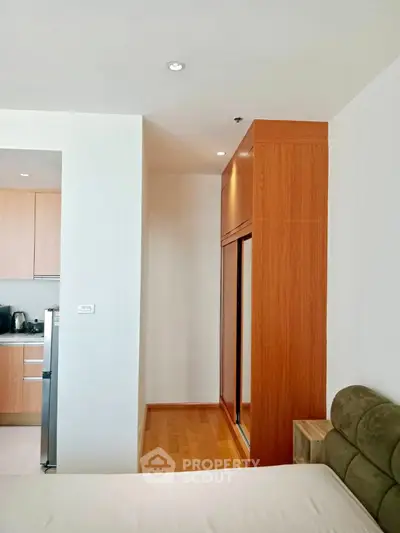 Modern apartment interior with sleek kitchen and cozy living area, featuring wooden cabinetry and contemporary design.