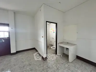 Spacious bathroom with tiled floor and simple fixtures, ideal for renovation.