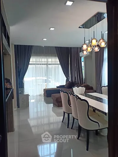 Elegant living and dining area with modern lighting and large windows in a stylish home.