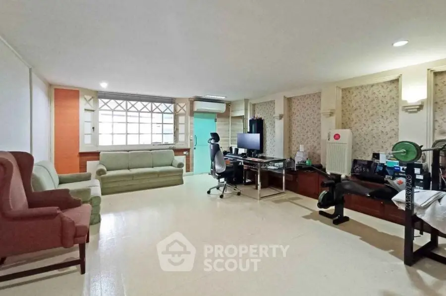 Spacious living room with modern decor and home office setup, perfect for work and relaxation.