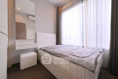 Cozy bedroom with natural light and modern furnishings in a stylish apartment.