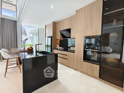 Luxurious modern kitchen with sleek black island and wooden cabinetry, featuring open layout and natural light.