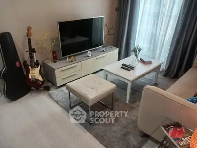 Modern living room with stylish decor, featuring a flat-screen TV, guitar, and cozy seating area.
