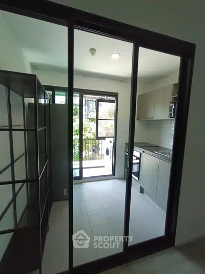 Modern kitchen with open layout and balcony view, featuring sleek cabinetry and appliances.