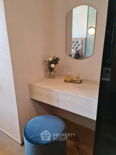 Elegant bedroom vanity with mirror and plush stool in modern apartment