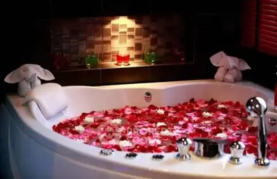 Luxurious bathroom with elegant bathtub adorned with rose petals and ambient lighting.