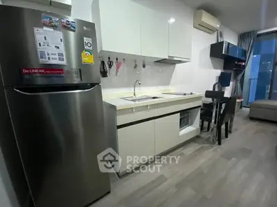 Modern kitchen with sleek appliances and dining area in stylish apartment.