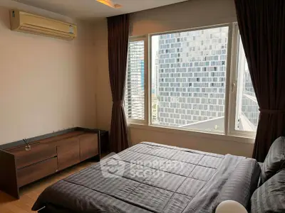 Modern bedroom with large window offering city view, featuring sleek furniture and air conditioning.