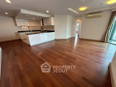 Spacious open-plan living room with hardwood floors and modern kitchen.