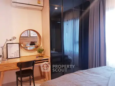 Cozy bedroom with stylish decor, featuring a wooden desk, round mirror, and large wardrobe with mirrored doors.