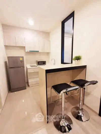 Modern kitchen with sleek bar stools and compact appliances in a stylish apartment.
