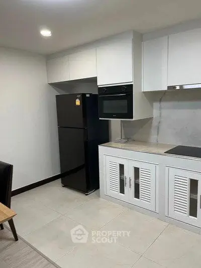 Modern kitchen with sleek cabinets and appliances, featuring a built-in oven and spacious fridge.