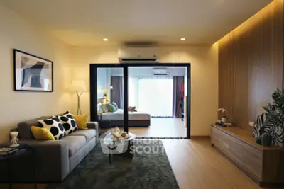 Modern living room with stylish decor and open view to bedroom, featuring cozy sofa and elegant lighting.