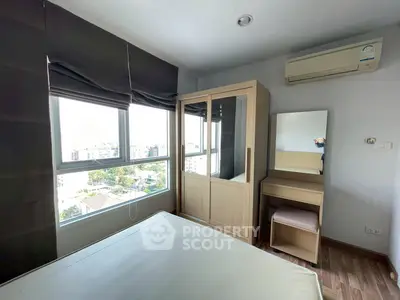 Cozy bedroom with large windows and modern furniture in a high-rise apartment.