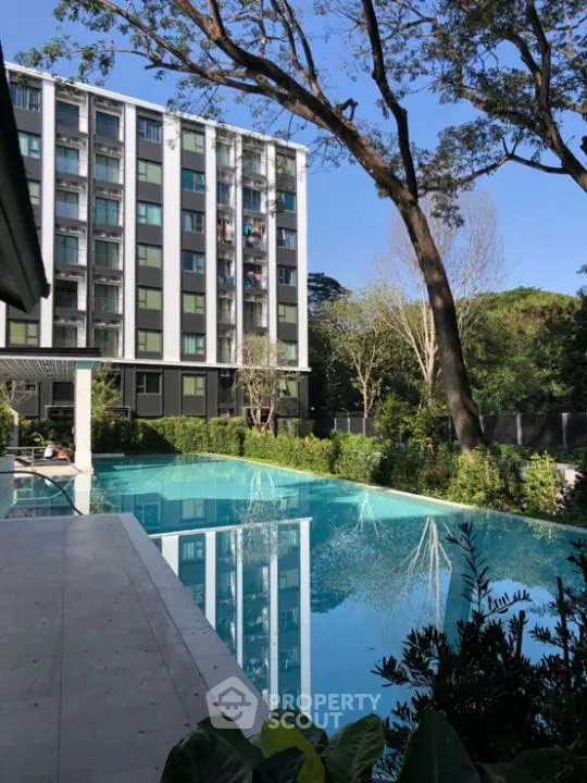 Modern apartment building with serene pool and lush greenery, perfect for relaxation and luxury living.