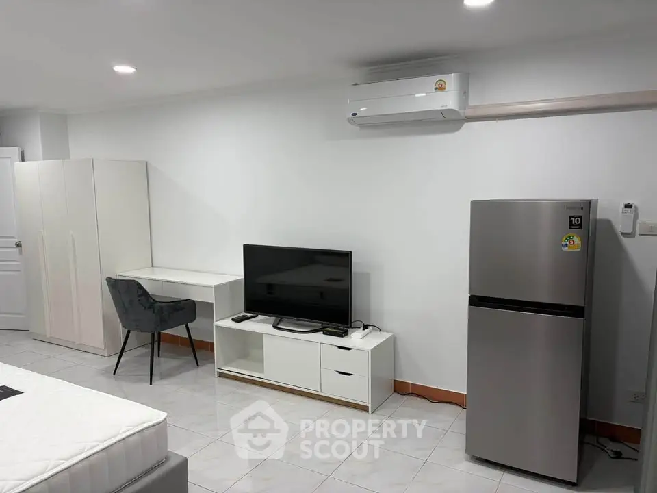 Modern studio apartment with sleek furniture and air conditioning, featuring a compact kitchen area and cozy living space.