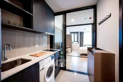 Modern apartment kitchen with washing machine and open layout to bedroom