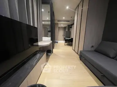 Modern living room with sleek design and large TV, featuring elegant wood flooring and contemporary furniture.