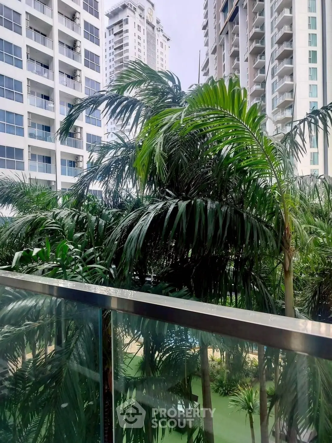 Luxurious high-rise buildings with lush greenery and glass balcony view.
