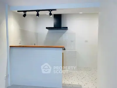 Modern kitchen with open layout and sleek design featuring white tiles and wooden countertop.