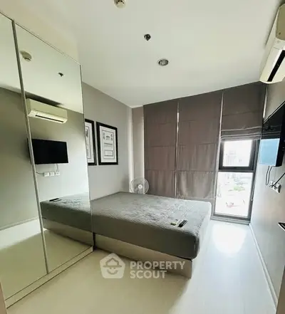 Modern bedroom with mirrored wardrobe and city view window.