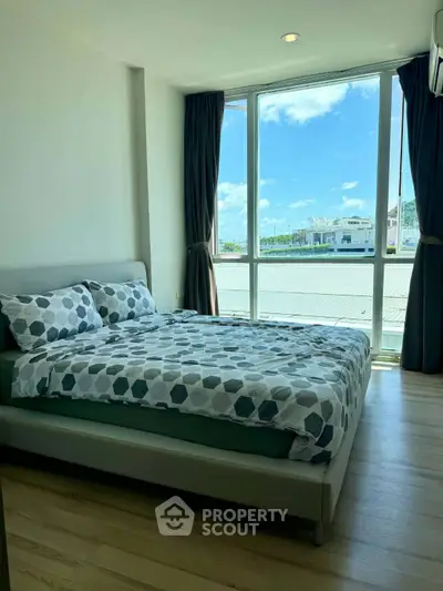 Bright bedroom with large window and modern decor, offering a serene view and ample natural light.