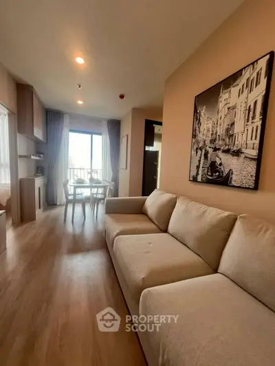 Spacious living room with modern decor and large window offering natural light and city view.
