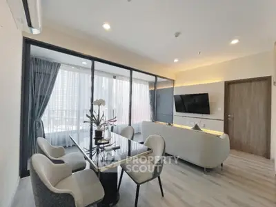 Modern living room with elegant dining area and large windows in a stylish apartment.