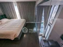 Modern bedroom with large windows and elegant curtains, featuring a sleek bed and dark wood flooring.