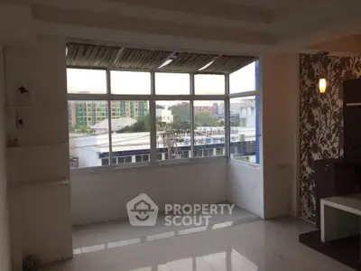 Spacious room with large windows offering city view and modern decor.