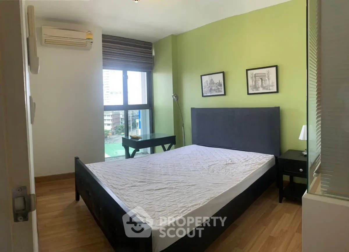 Modern bedroom with green accent wall and large window view