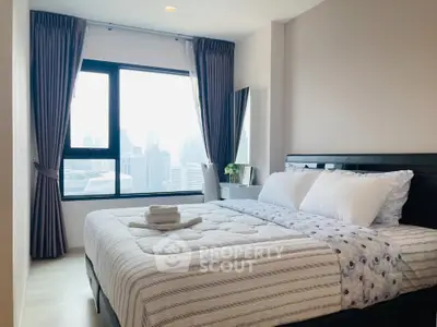 Modern bedroom with city view, featuring a cozy bed and large window.