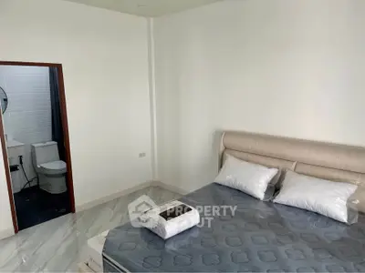 Modern bedroom with ensuite bathroom featuring sleek design and neutral tones.
