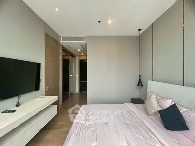 Modern bedroom with sleek design and wall-mounted TV, featuring soft lighting and elegant decor.