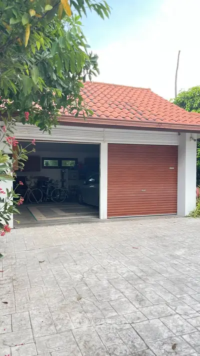 Charming garage with red-tiled roof and open doors revealing bicycles and a car inside.