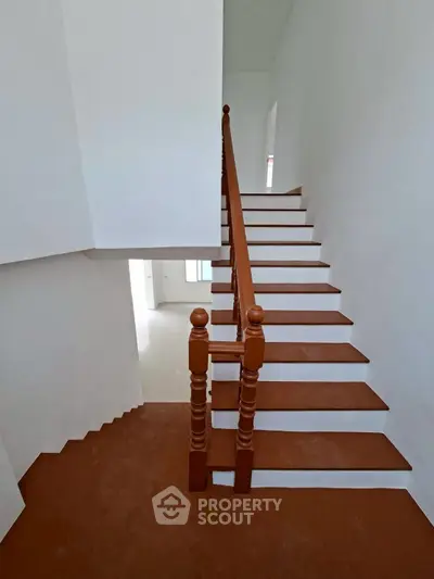 Elegant wooden staircase in a modern home with white walls and natural light.