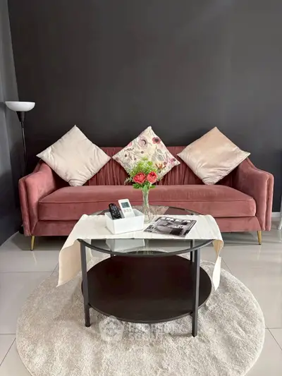 Stylish living room with pink velvet sofa, chic decor, and modern glass coffee table.