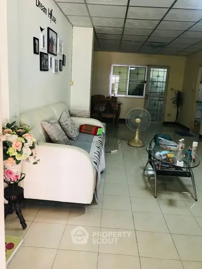 Cozy living room with white sofa and glass coffee table in a well-lit space.