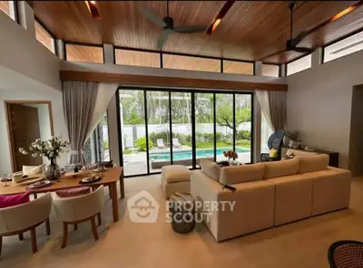 Luxurious living room with pool view, high ceilings, and elegant decor in modern home.