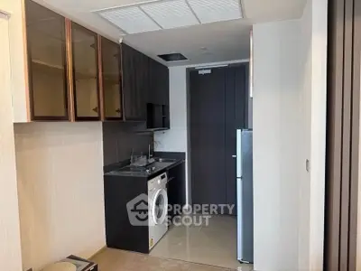 Compact kitchen with washing machine and modern cabinetry in a stylish apartment.