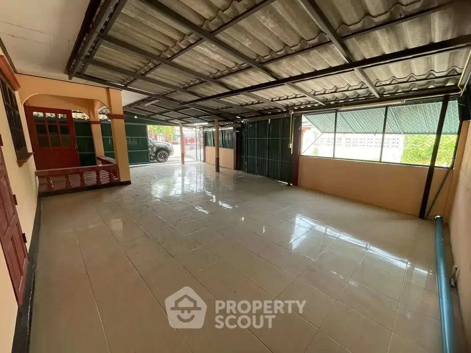 Spacious covered parking area with tiled flooring and metal roofing, ideal for multiple vehicles.